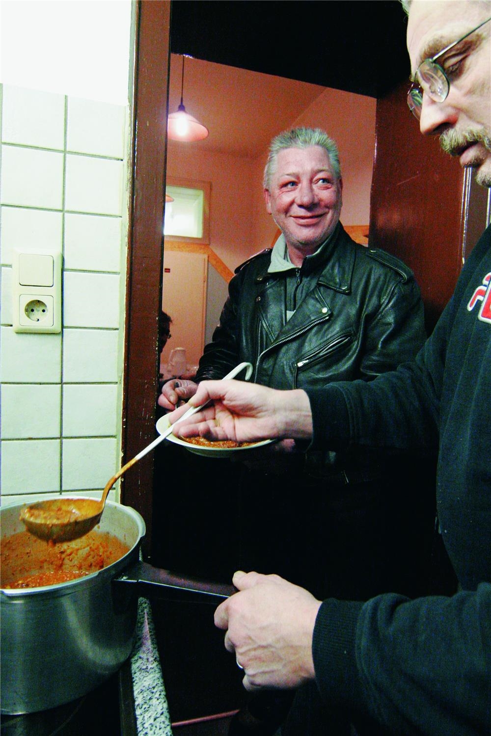 Zwei Männer in der Küche bei der Essensausgabe (Foto: Bergmoser+Höller)