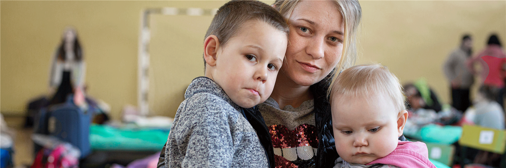 Eine ukrainische Mutter mit ihren beiden Kindern im Arm. Angekommen in einer Caritas Unterkunft für Geflüchtete.