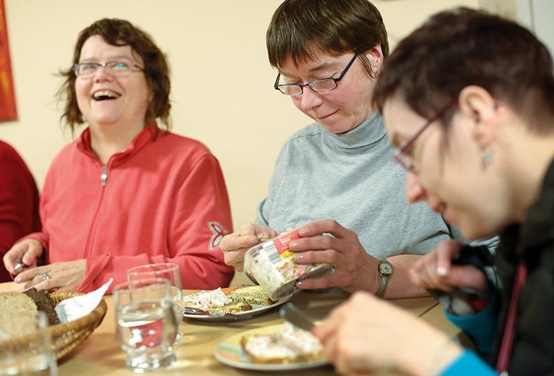 Drei Frauen mit Behinderung am Tisch beim Abendbrot. (Thilo Schmülgen, Aktion Mensch)