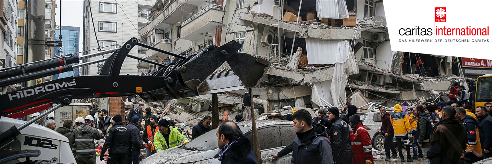 Menschen in der Türkei und in Syrien stehen vor den Trümmern eingestürzter Häuser. Die Caritas leistet Nothilfe vor Ort.  