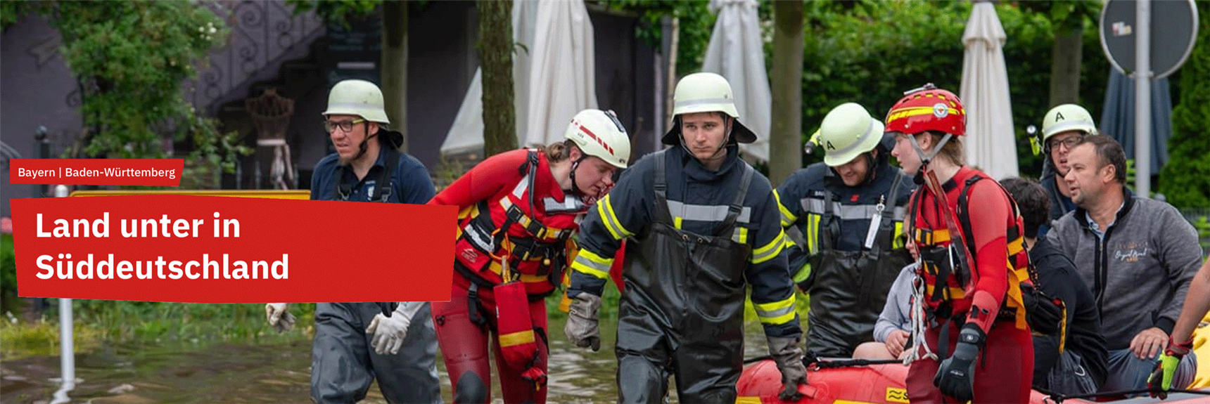 Hochwasserhilfe: Feuerwehr und Helfer:innen der Wohlfahrt ziehen ein Boot auf dem Wasser. Die Caritas unterstützt mit Notunterkünften. 