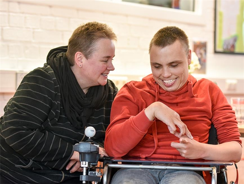 Mitarbeiter der Caritas mit einem Mann mit Behinderung