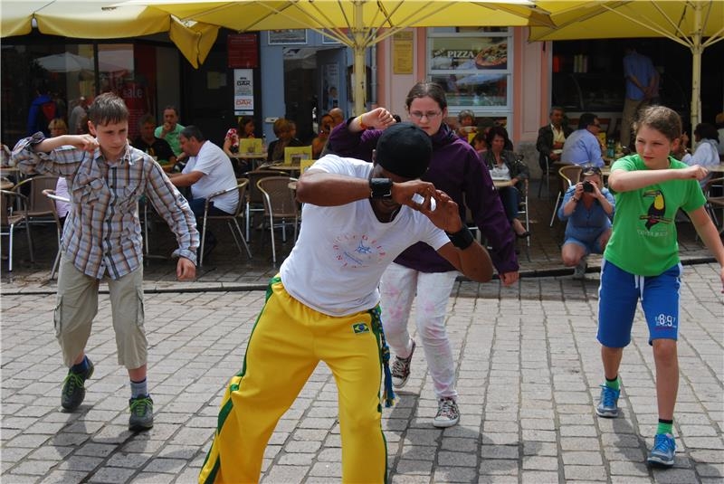 Drei Jugendliche nehmen an einem kleinen Capoeira Workshop teil. 