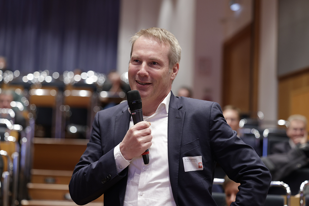 Dr. Nils Brüggemann (Vorstandsvorsitzender der Franziskus Stiftung Münster) steht beim 2. Kath. Krankenhaustag am 21.11.2023 in Essen im Publikum und stellt eine Frage  (Foto: Achim Pohl)