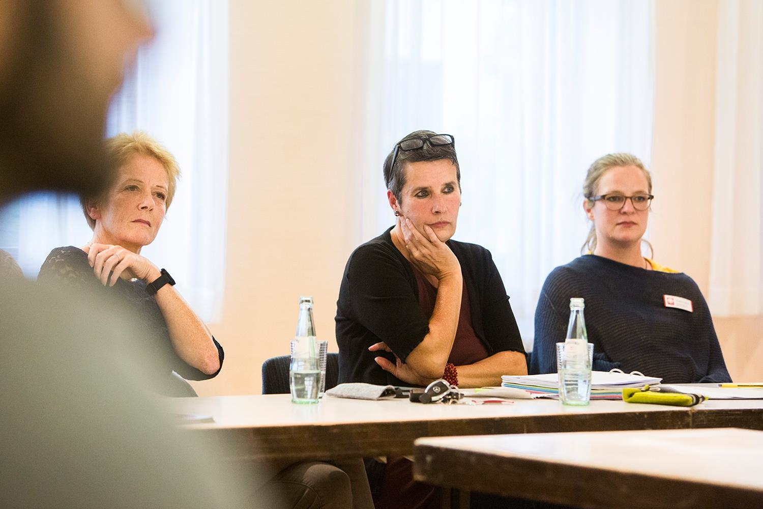 Drei Frauen sitzen an einem Tisch und hören etwas oder jemandem außerhalb des Bildes zu (Deutscher Caritasverband e. V. / Sebastian Pfütze)