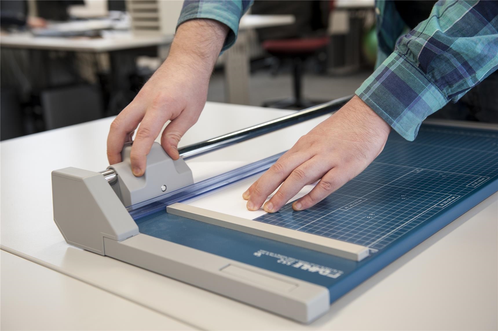Hände schneiden Papier mit einer Maschine in der Jugendwerkstatt Büro und EDV der CJS Hannover (Ina Funk)