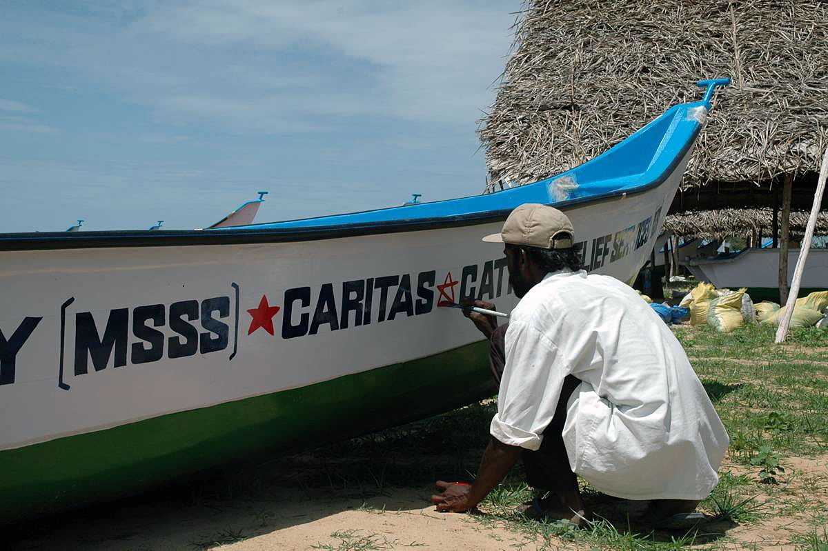 Ein Mann aus Sri Lanka bemalt ein Boot.