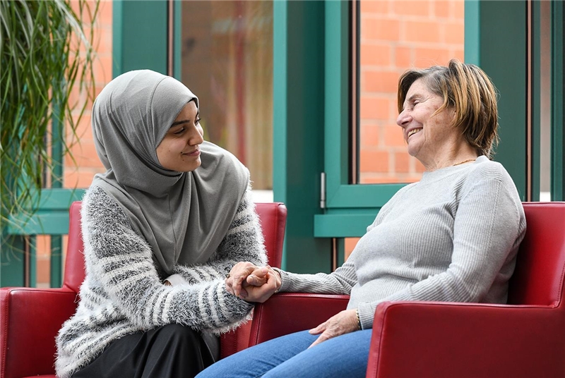 Das Foto zeigt eine junge Frau mit Kopftuch im Gespräch mit einer älteren Frau.