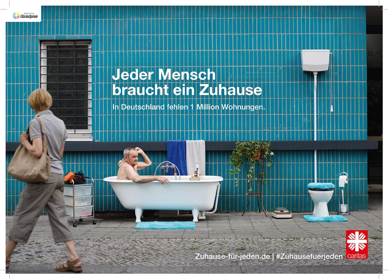 Das Foto zeigt einen Mann, der in einer Badewanne auf der Straße sitzt und sich wäscht.