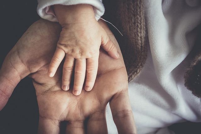 Baby-Hand liegt auf Hand eines Erwachsenen