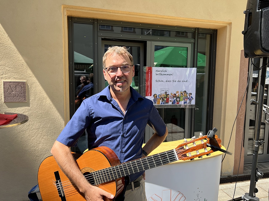 Mann mit akustischer Gitarre vor einem Gebäude (Caritasverband Darmstadt e. V. / Jens Berger)