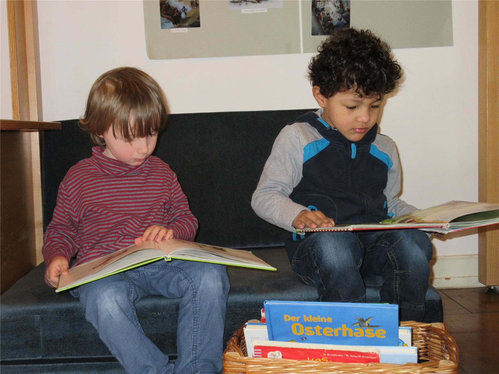 Zwei Jungen sitzen auf einem Sofa und schauen in Bücher (Caritasverband Trier e. V.)