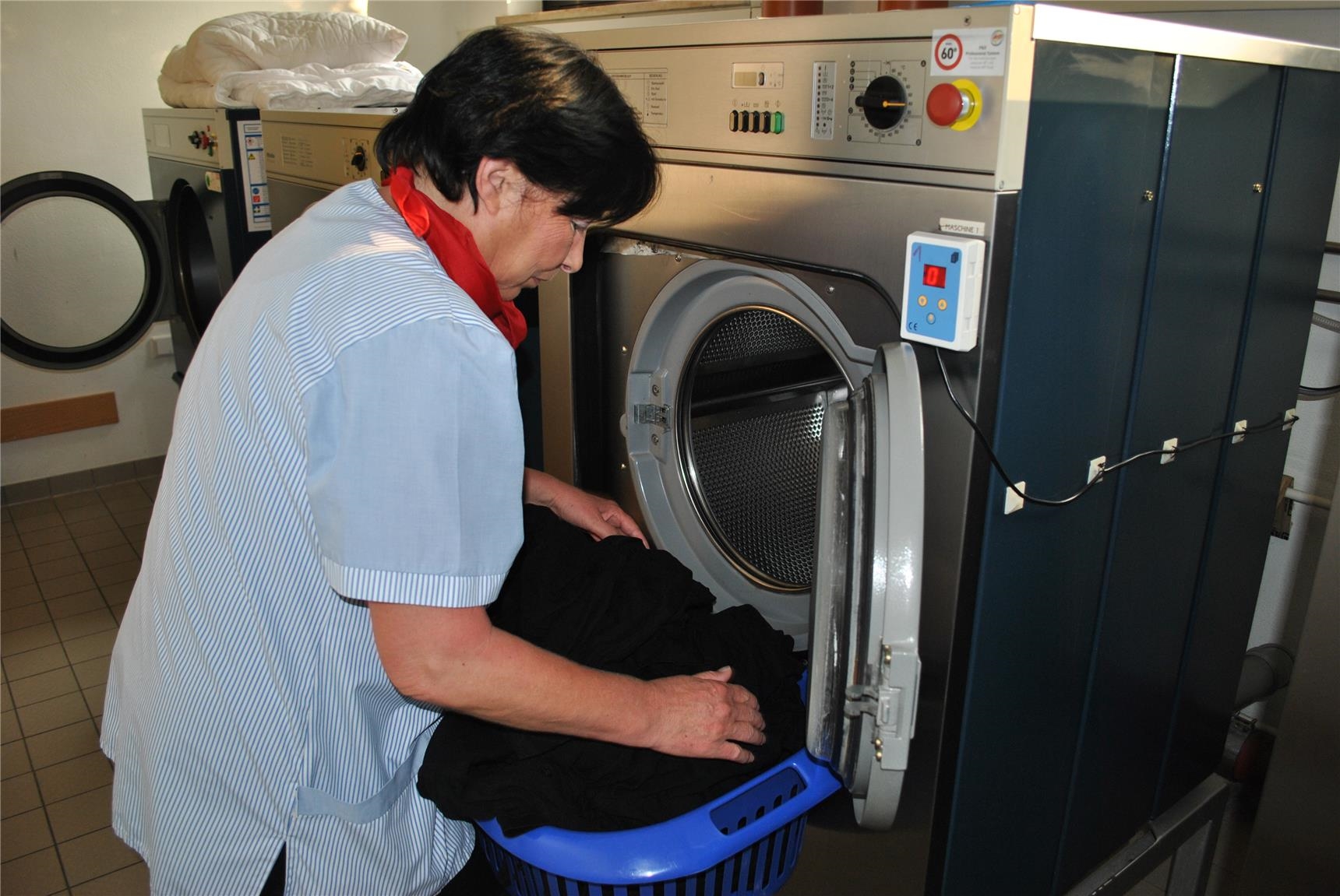 Hauswirtschaftsmitarbeiterin befüllt eine Waschmaschine 