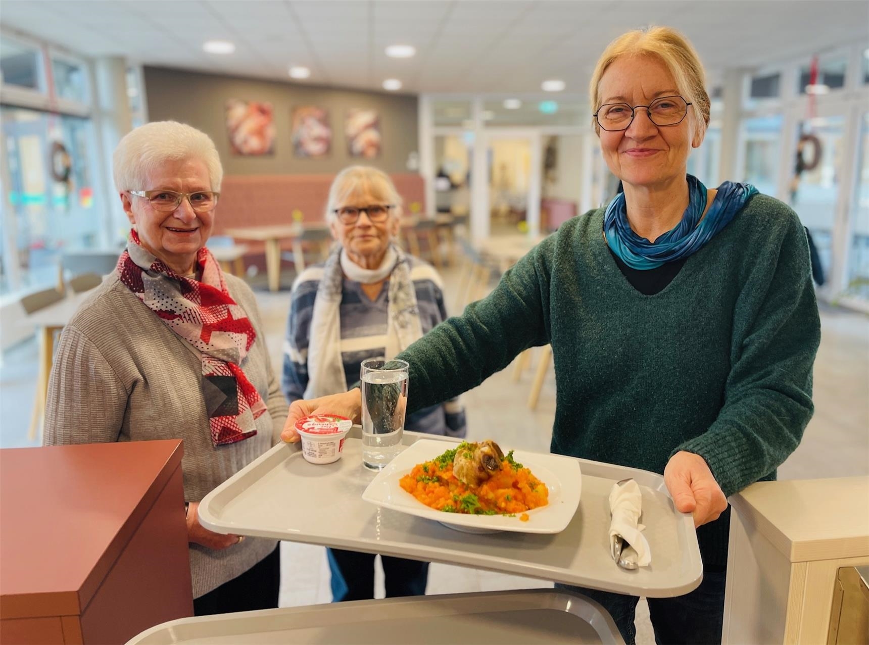 Sozialarbeiterin trägt alter Dame das Tablett mit Eintopf