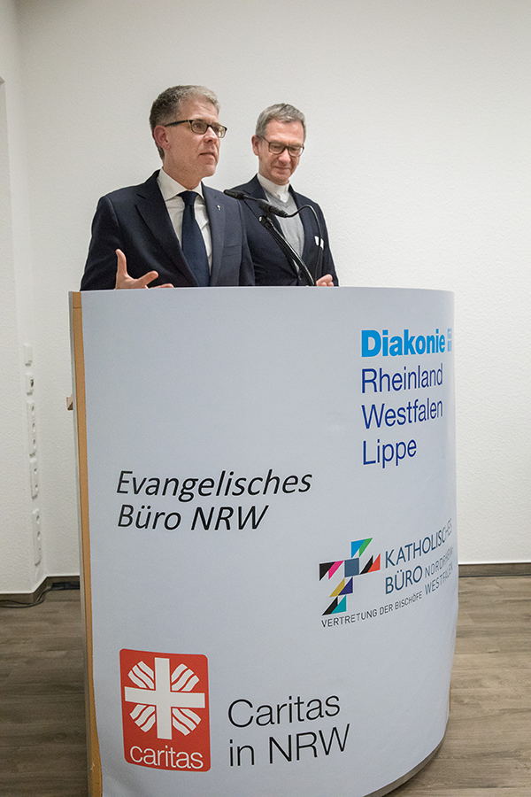 Kirchenrat Dr. Thomas Weckelmann und Dr. Antonius Hamers stehen zusammen am Rednerpult auf der Fachveranstaltung zur Krankenhausfinanzierung in Düsseldorf (Achim Pohl)