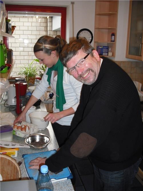 Bewohner und Mitarbeiterin lachend, bei der Essenszubereitung in der Küche (©caritasverband bocholt)