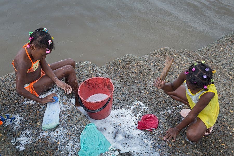 zwei Mädchen am Fluss beim Waschen der Kleidung (Jürgen Escher, 2016)