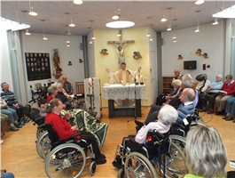 Im Kapellenraum steht der Pfarrer hinter dem Altar und davor sitzen Bewohner im Rollstuhl / Foto: Schedlbauer