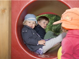 Zwei Kinder sitzen draußen in einer Röhre vom Spielbereich / Dietmar Wäsche