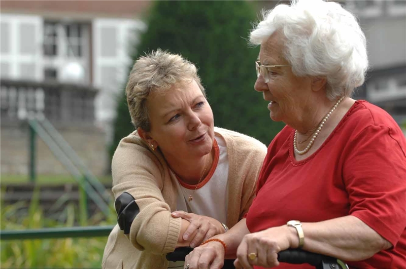 Zwei Frauen reden im Freien miteinander; eine ist alt, eine jünger