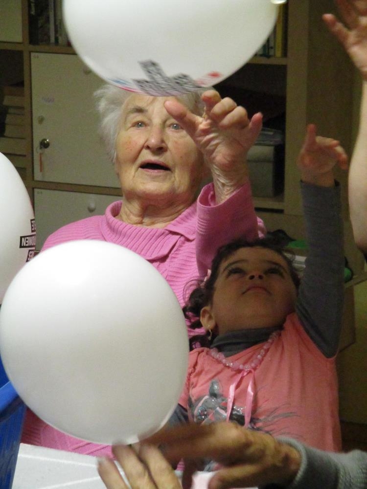 Eine Seniorin und ein junges Mädchen beim Spielen mit Ballons. (Caritas Tagespflege Heilig Geist)