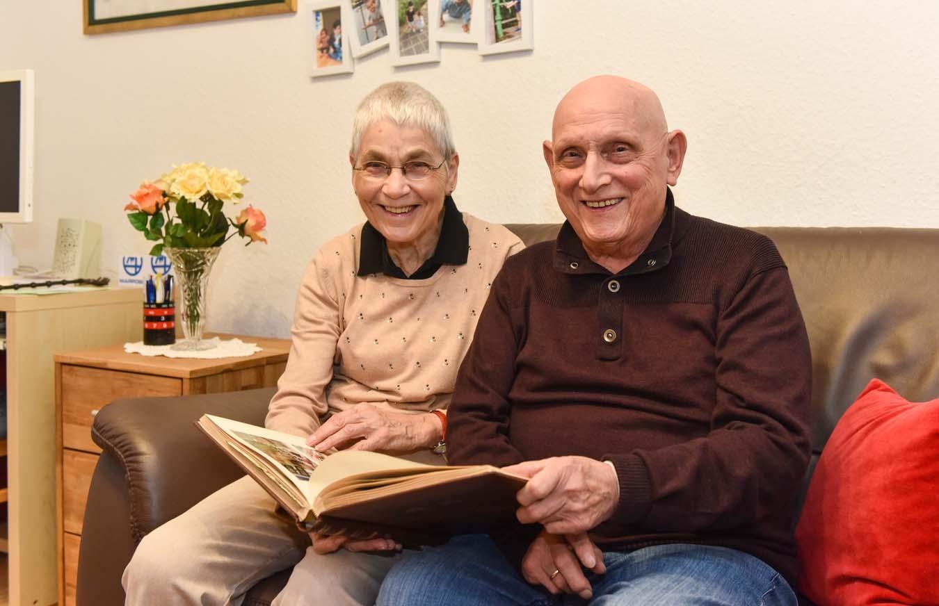 Ein älteres Paar sitzt auf dem Sofa und hält ein Buch in den Händen