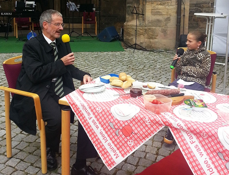 Mann und Kind am Tisch im Freien bei einem Interview (Barbara Fank-Landkammer)