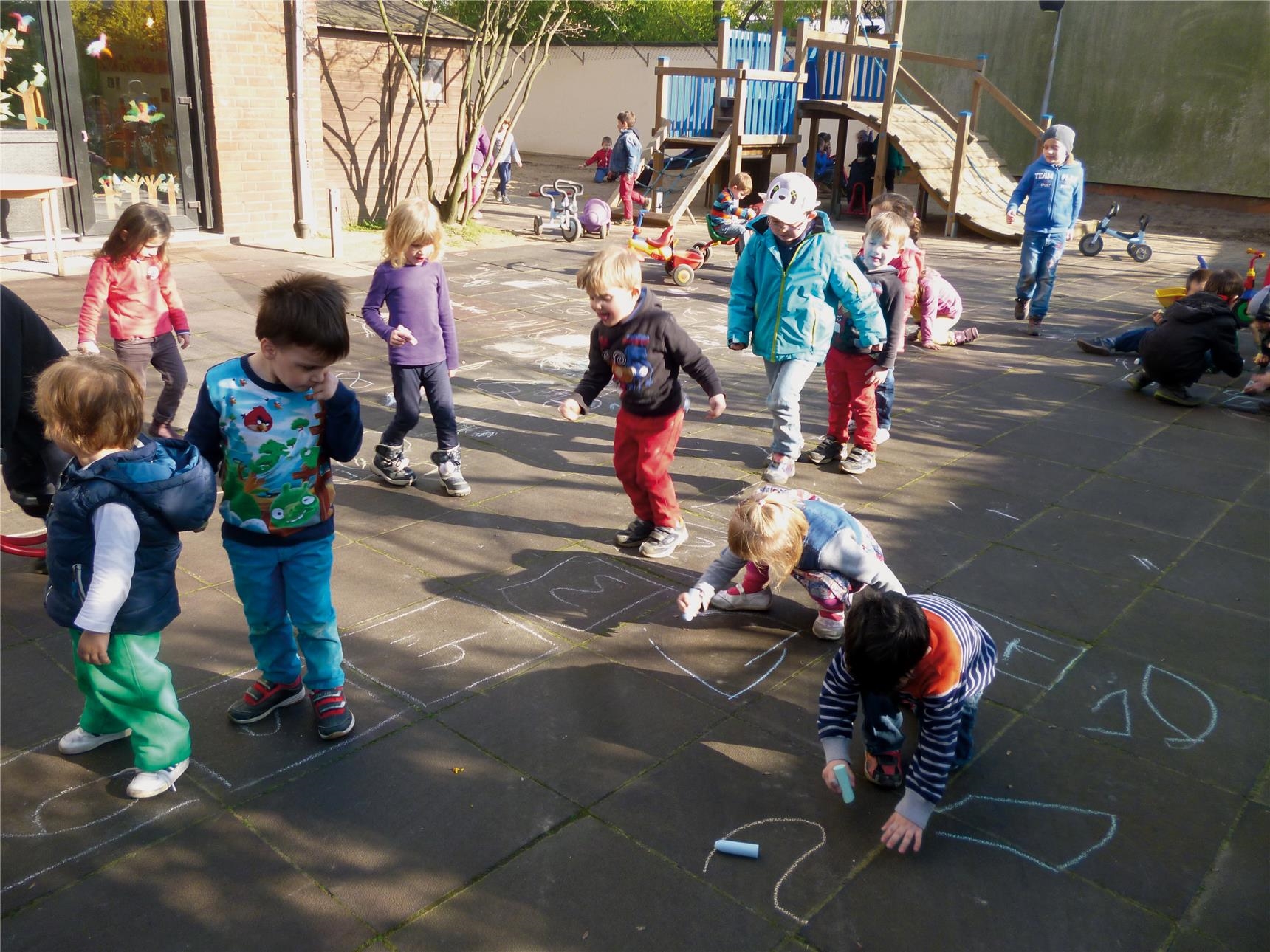 Viele Kinder spielen bei schönem, sonnigen Wetter auf dem Hof der Kindertagesstätte 