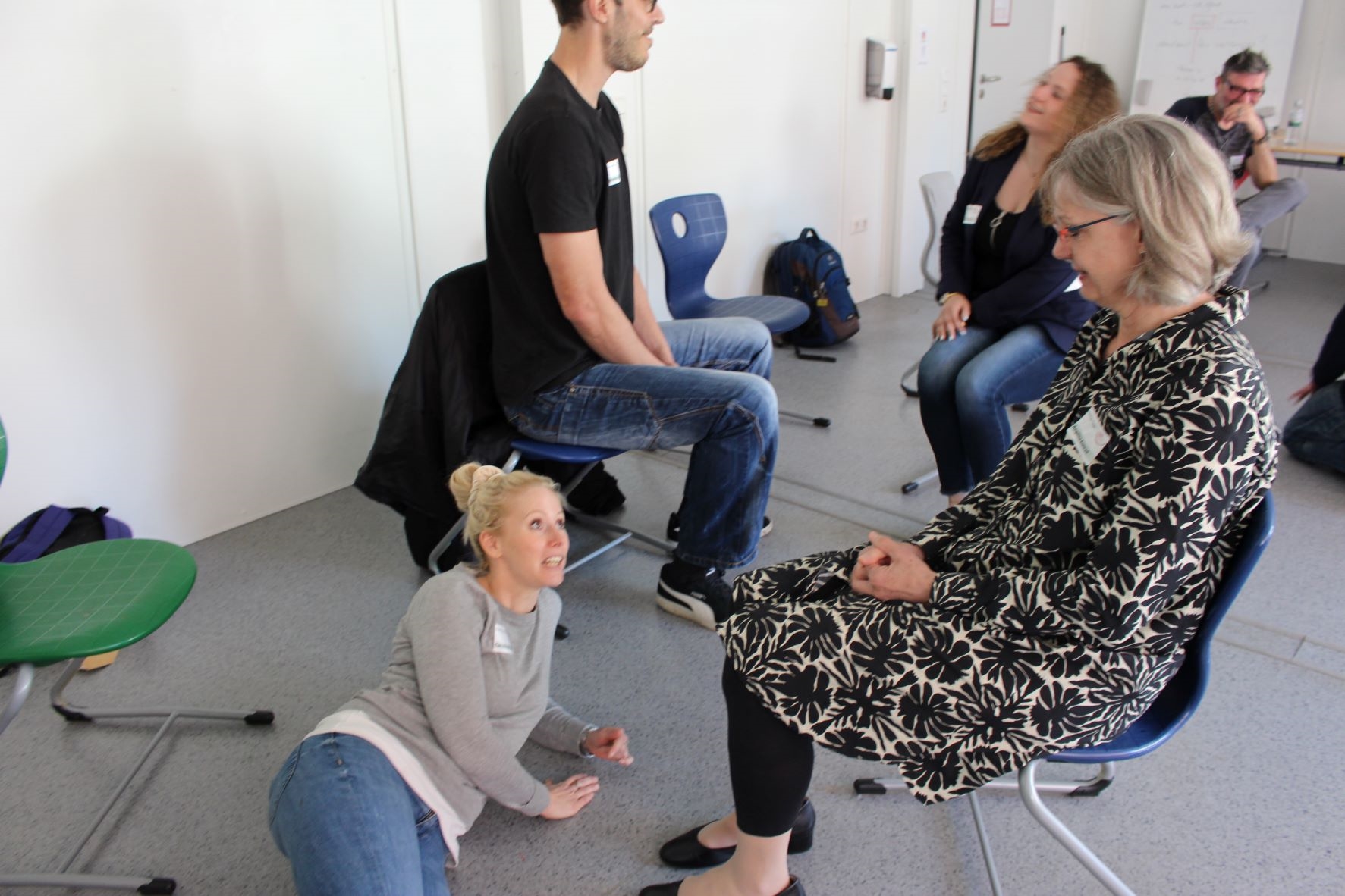 Eine Frau blickt vom Boden zu einer nach, die sitzt. (Caritasverband Darmstadt e. V.)