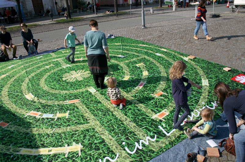 Kinder laufen über eine Matte, auf der ein Labyrinth abgebildet ist 