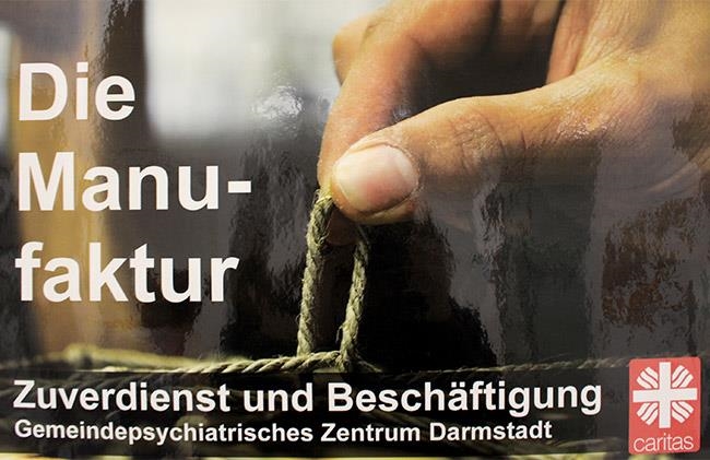 Schild mit der Beschriftung Die Manufaktur – Zuverdienst und Beschäftigung (Caritasverband Darmstadt e. V.)