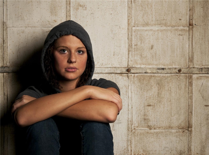 Junge Frau sitzt vor einer Wand