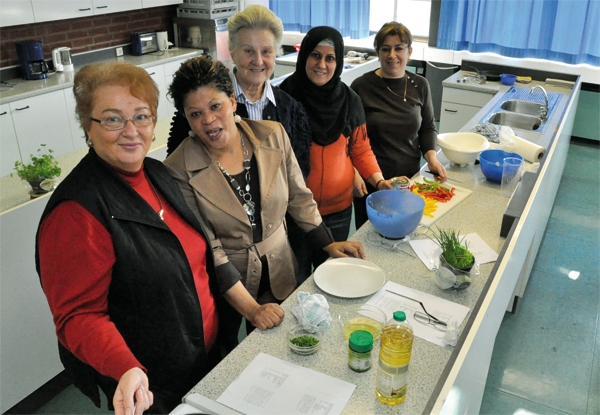 Vier Teilnehmerinnen und eine Mitarbeiterin der Caritas-Konferenzen (Mitte) stehen an einer Küchenzeile und bereiten Speisen zu. (Jürgen Sauer)