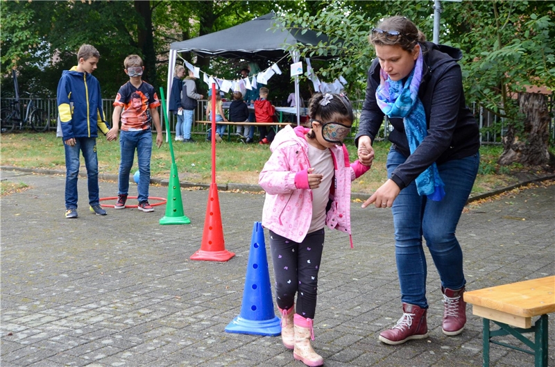 Beim Kinderrechte-Fest in Breyell führt Nora Campen, Leiterin des Bürgerbüros Breyell, ein Mädchen mit Augenmaske durch den Hindernis-Parcours.