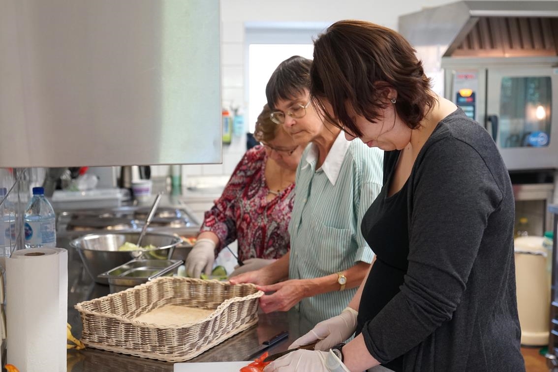 Drei Frauen in einer Küche, beschäftigt mit Schneidetätigkeiten (Caritasverband Trier e. V.)