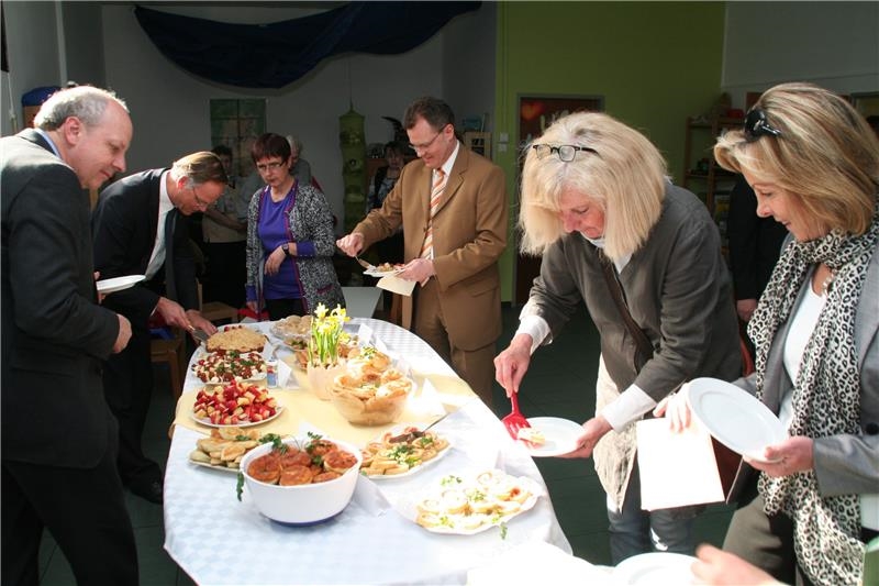 Das Foto zeigt Menschen, die sich an einem reich gedeckten Tisch bedienen.  (Harald Westbeld)