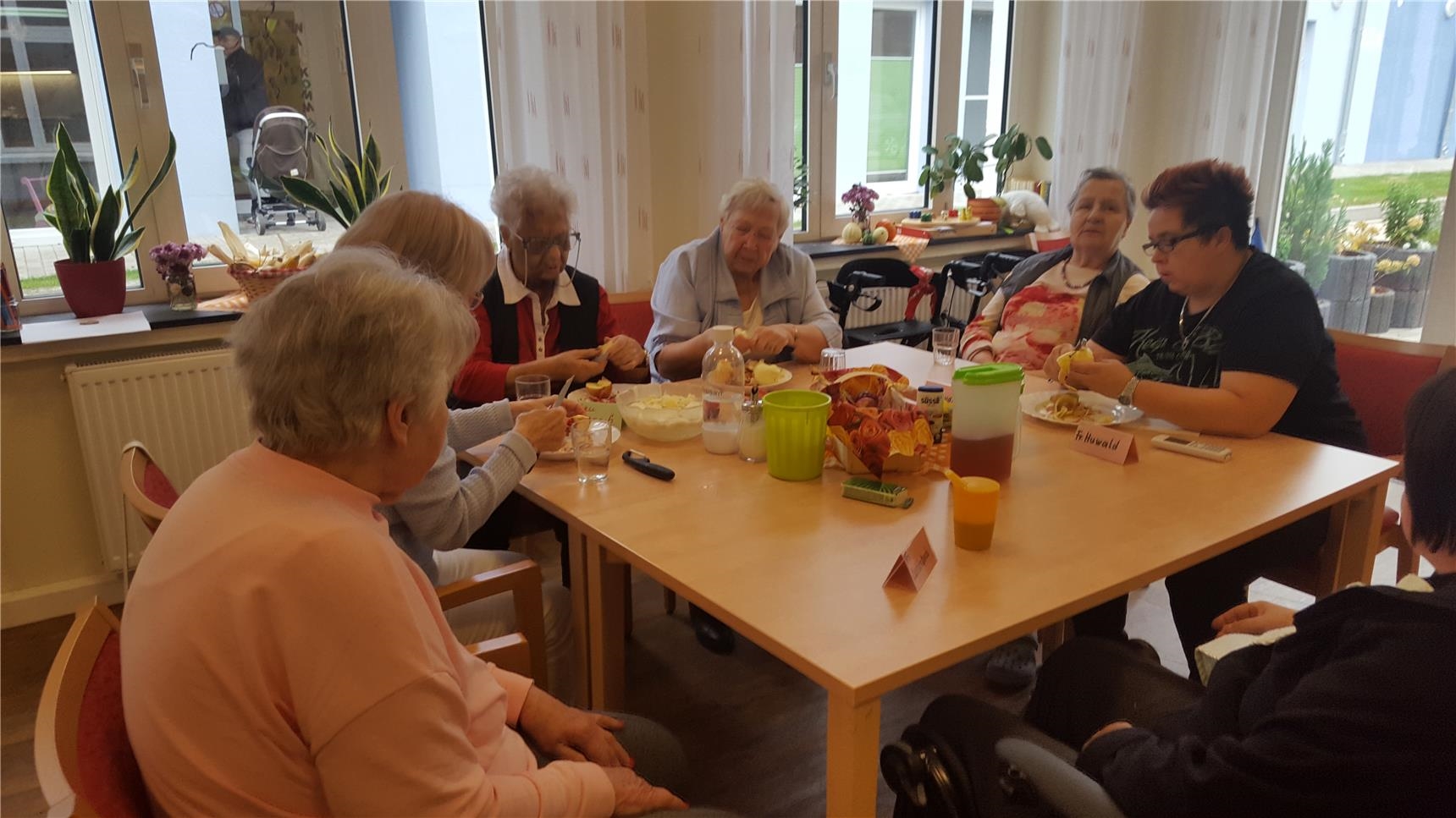 Senioren sitzen am Tisch und schälen Äpfel (Tagespflege St. Rochus)
