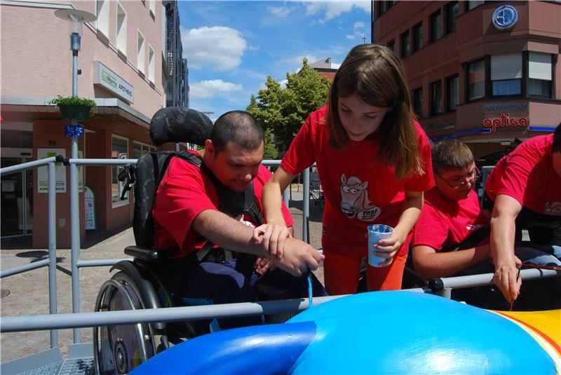 Mädchen unterstützt Rollstuhlfahrer beim Malen (Caritas Speyer)