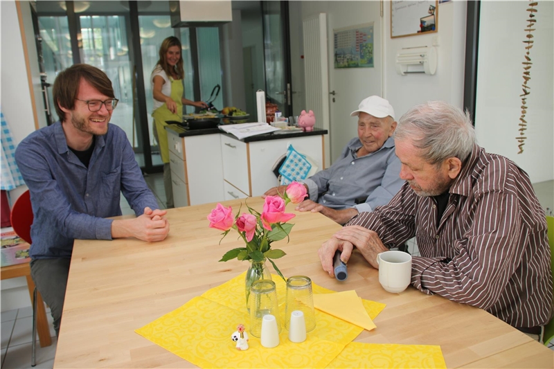 Drei Männer sitzen an einem Tisch und lachen.