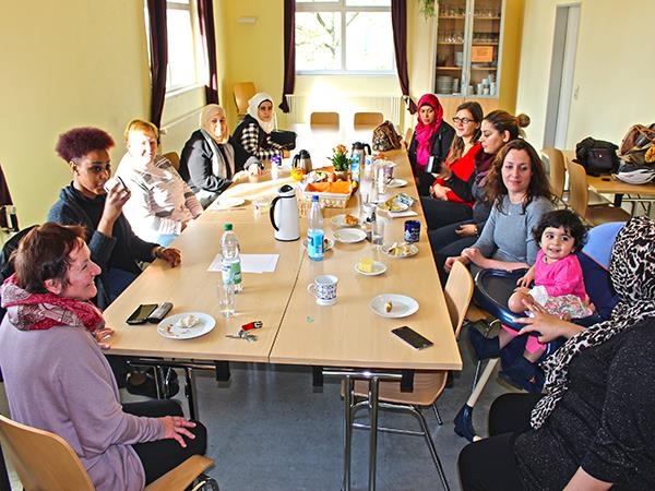 Eine Gruppe von 10 Frauen und ein Kleinkind am Frühstückstisch (Caritasverband Darmstadt e. V.)