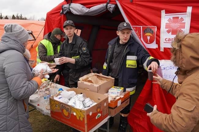 Helfer geben heiße Getränke an Menschen aus (Foto: Caritas Polen)
