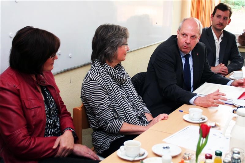 Das Foto zeigt vier Menschen, die sich nebeneinander sitzend an einem Tisch unterhalten.