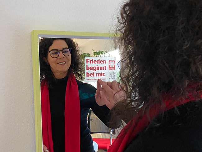 Caritasdirektorin Frau Rhein platziert den Friedensaufkleber auf Spiegel (Caritasverband Darmstadt e. V.)