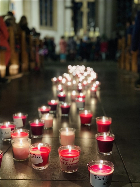Viele brennende Kerzen stehen im Kirchenschiff, der Hintergrund verschwimmt