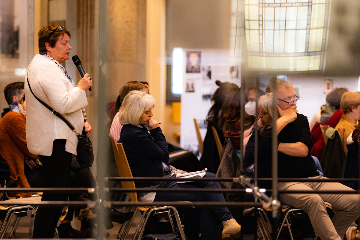 Eine Teilnehmerin der der CiNW-Fachtagung 'Miteinander Gegeneinander?' in der Alten Synagoge in Essen steht im Publikum und stellt eine Frage (Foto: © Angelika Kamlage | Caritas in NRW)