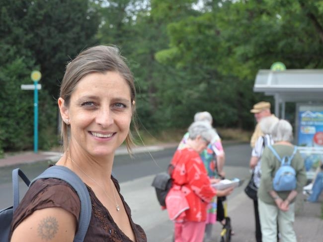 Alexandra Ladach lächelt in die Kamera vor einer Bushaltestelle