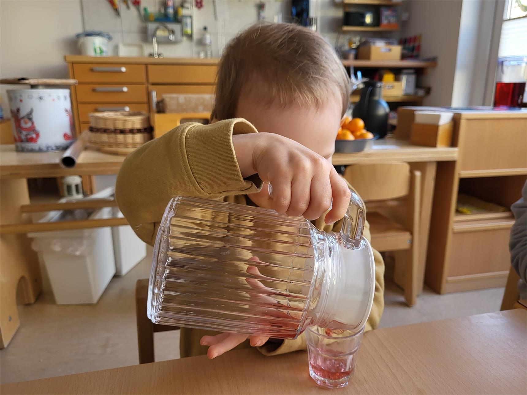 Kind schüttet sich ein Glas Wasser ein. 