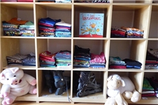 Wir blicken auf ein Regal, welches mit Kinderbekleidung befüllt ist. / Caritas Marburg