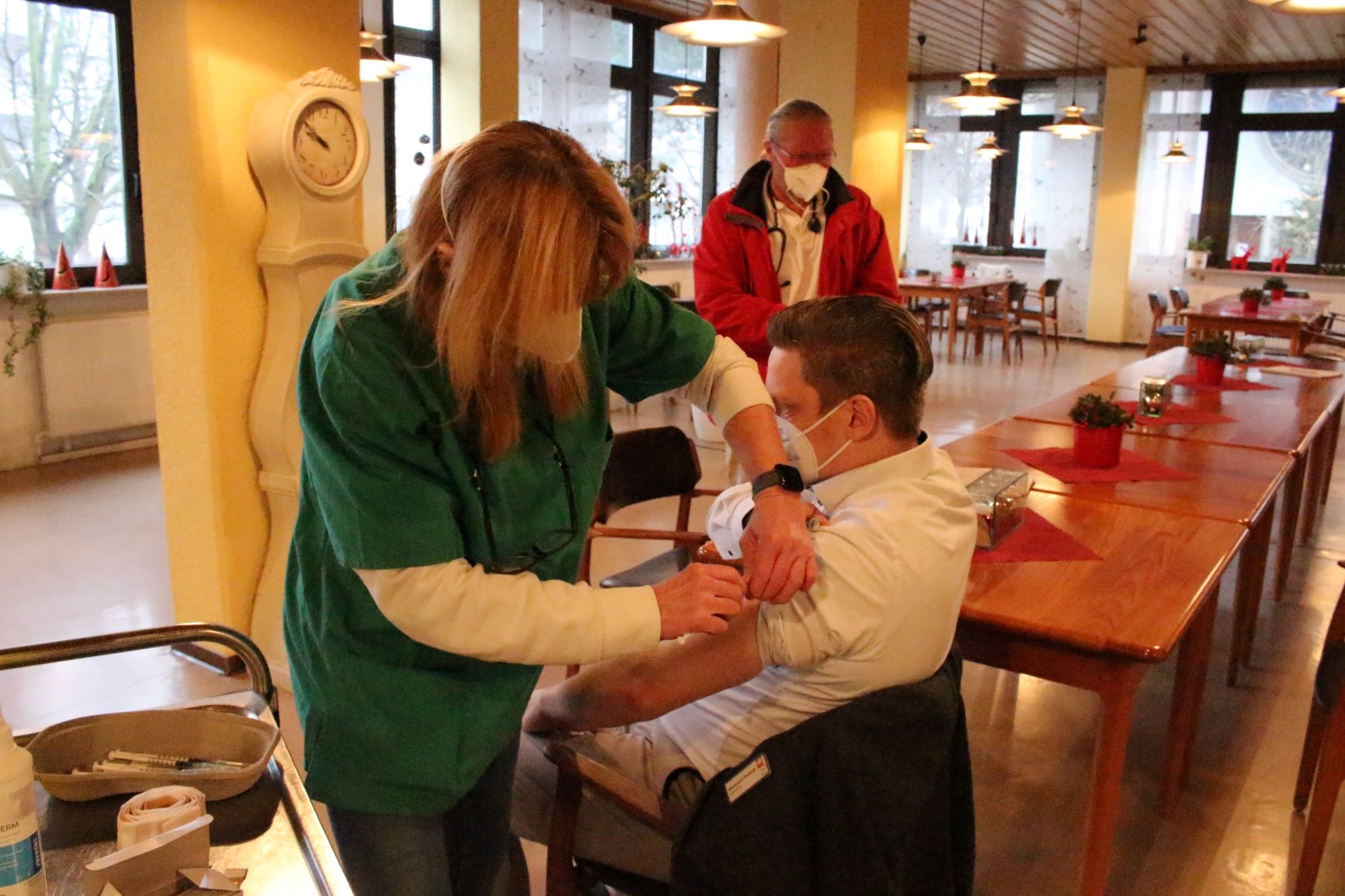 Männliche Person sitzt auf Stuhl und erhält von einer Frau eine Impfung. (Caritasverband Darmstadt e. V.)