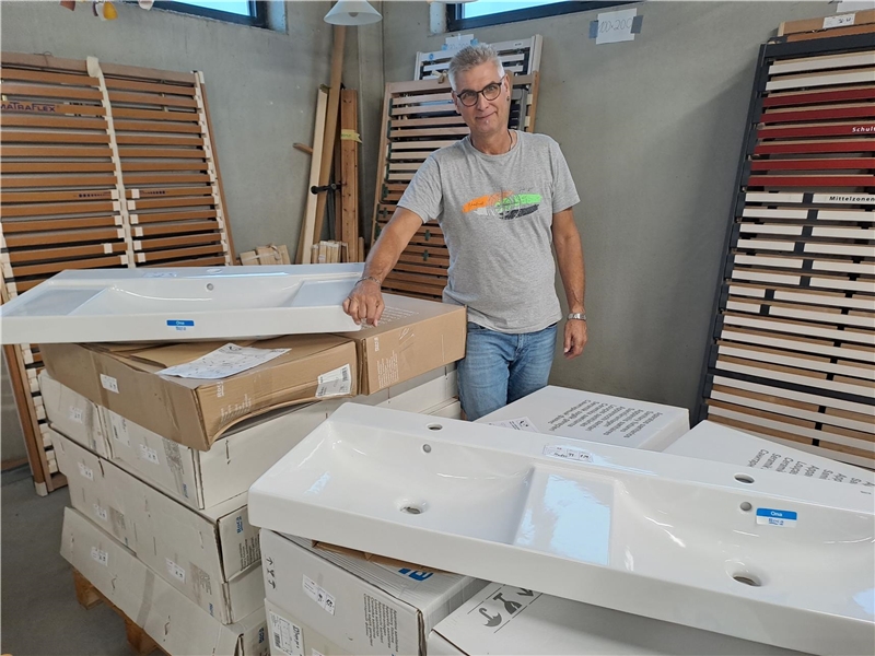 Werner Mayr, Leiter des Caritas-Möbellagers in Leipheim freut sich über die  vor ihm gezeigten neuen Waschbecken. 